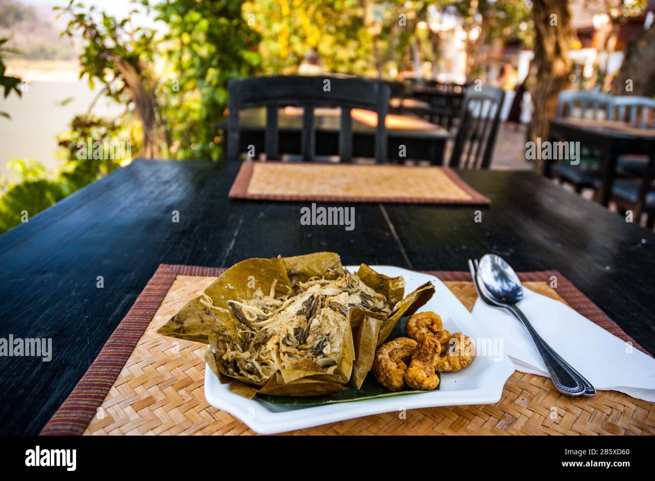 Mok, ni de poulet de l'ami et de pousses de bambou à la vapeur dans une feuille de bananier dans un restaurant au bord du Mékong à Luang Prabang, Laos Banque D'Images