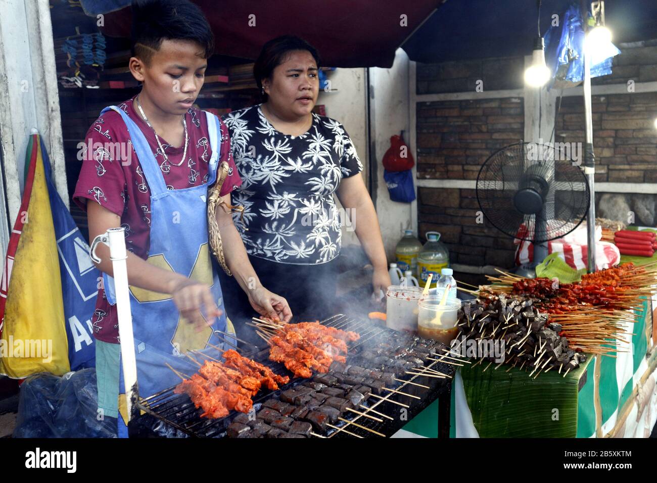 Antipolo, Rizal, Philippines - 24 février 2020: Le vendeur de nourriture de rue à son étalage de nourriture vend des innards de porc et de poulet grillés dans des bâtonnets de barbecue. Banque D'Images