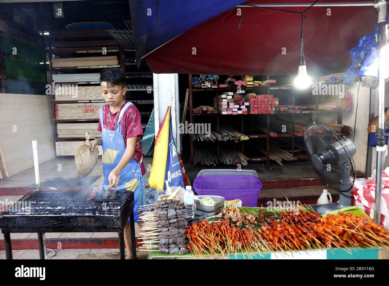 Antipolo, Rizal, Philippines - 24 février 2020: Le vendeur de nourriture de rue à son étalage de nourriture vend des innards de porc et de poulet grillés dans des bâtonnets de barbecue. Banque D'Images
