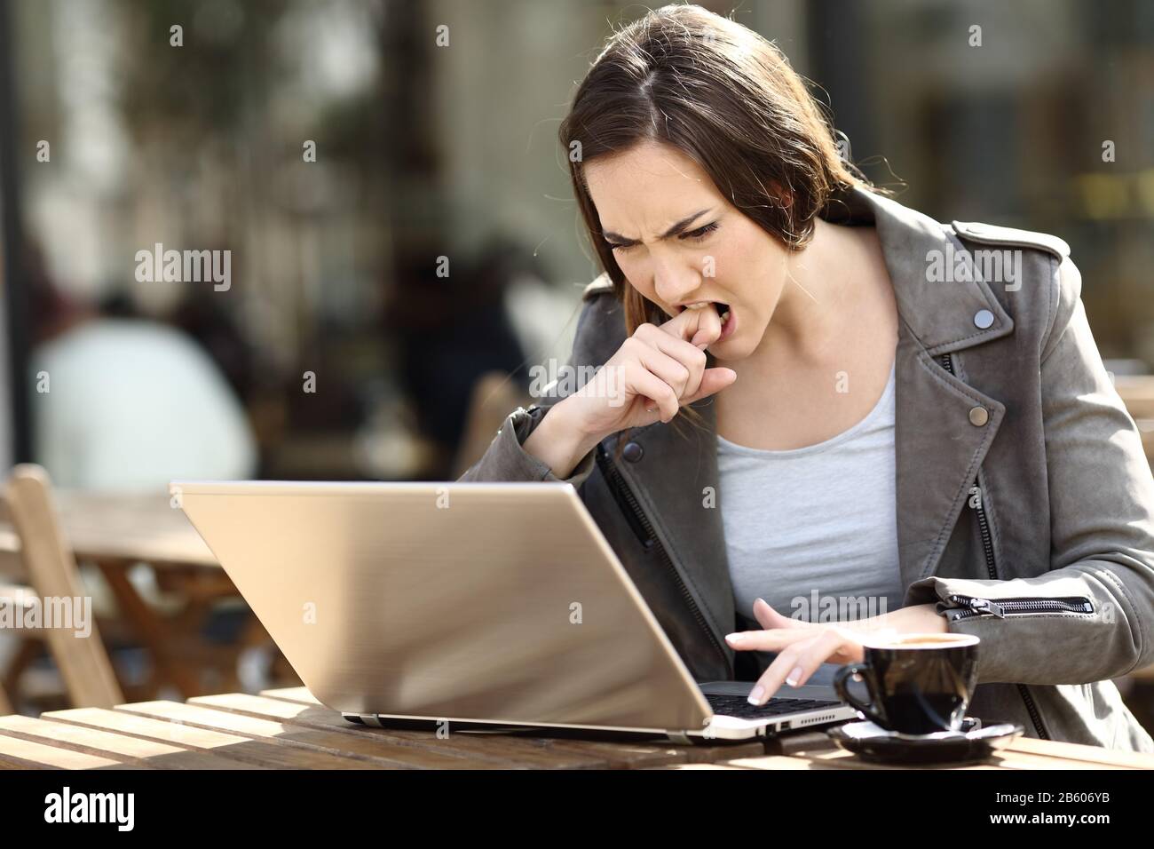 Une fille en colère appuyant sur le bouton frustrée d'utiliser son ordinateur portable sur une terrasse de café Banque D'Images