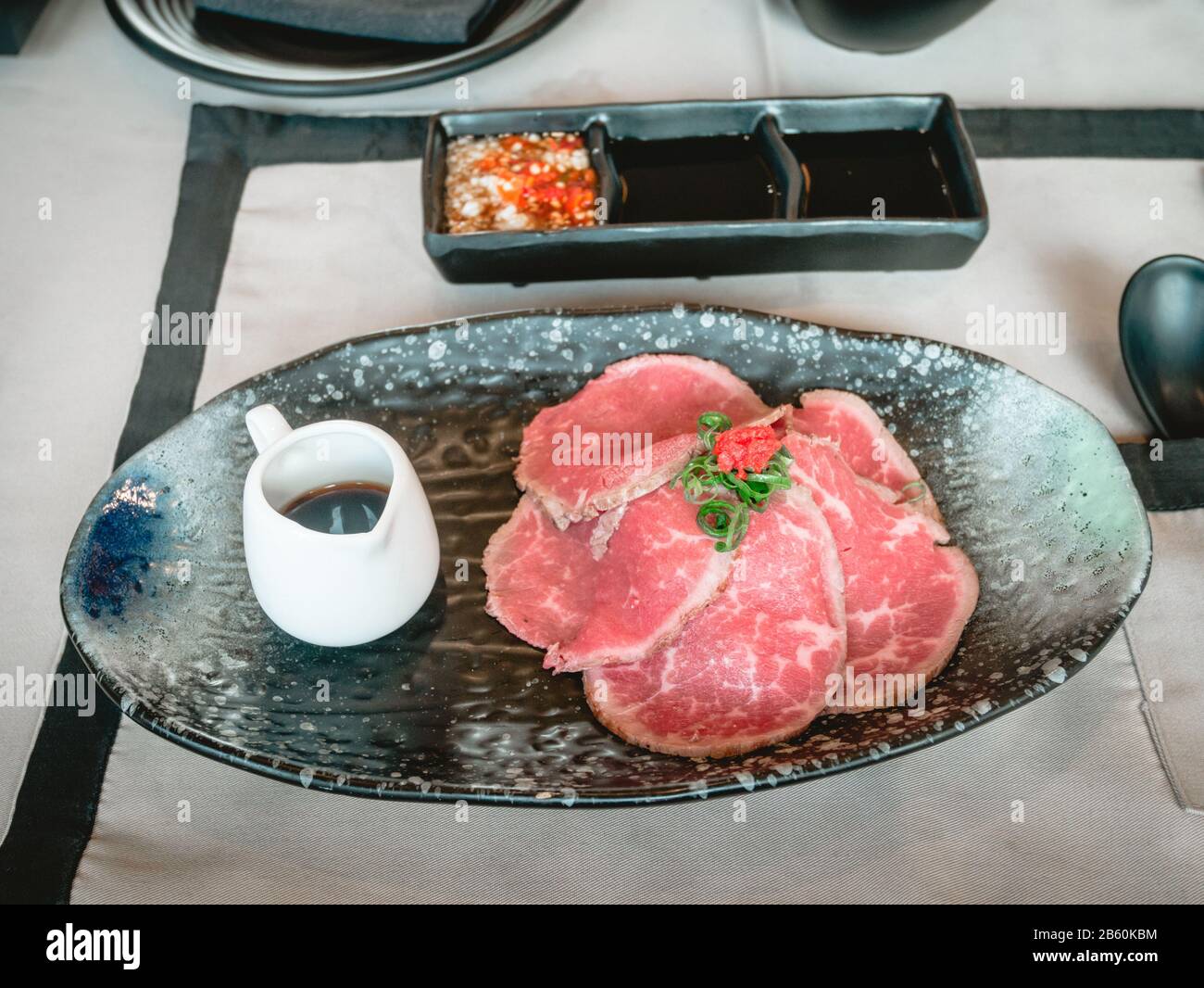 Tranches de bœuf de pari avec sauce ponzu dans une plaque en céramique noire sur la table du japon au restaurant. Banque D'Images