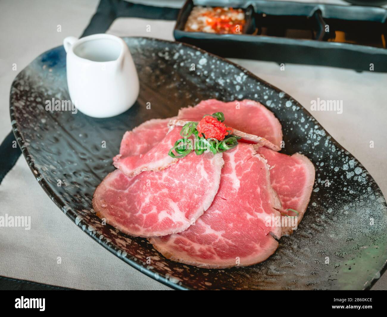 Tranches de bœuf de pari avec sauce ponzu dans une plaque en céramique noire sur la table du japon au restaurant. Banque D'Images