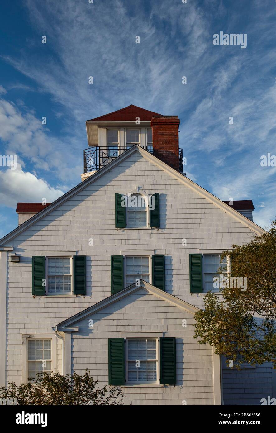 Une belle maison côtière sous ciel bleu clair avec parement en bois blanc et volets verts Banque D'Images