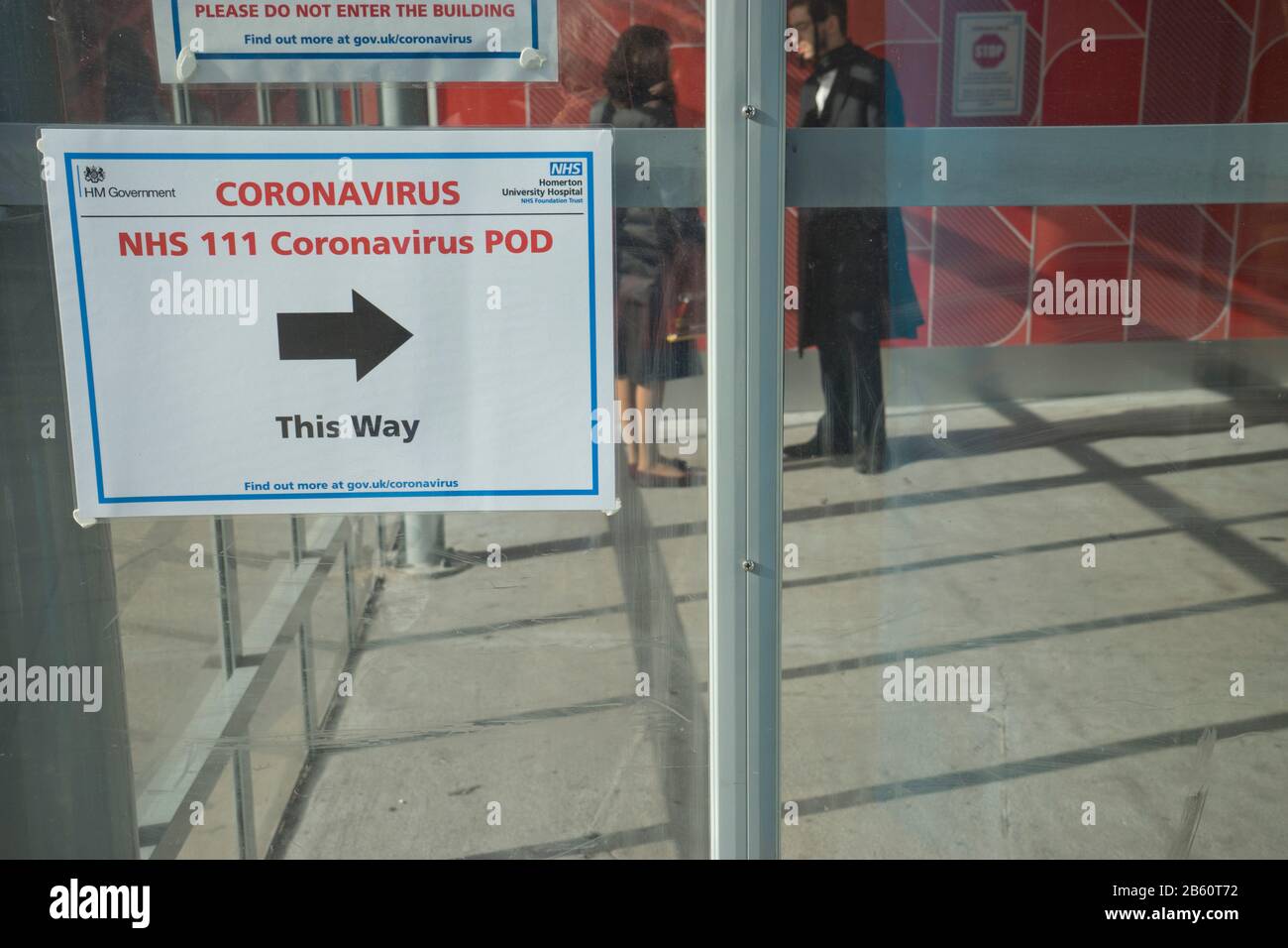 Les visiteurs marchent devant les panneaux indiquant Coronavirus pod à l'hôpital NHS de Homerton à Londres, en Angleterre, au Royaume-Uni Banque D'Images