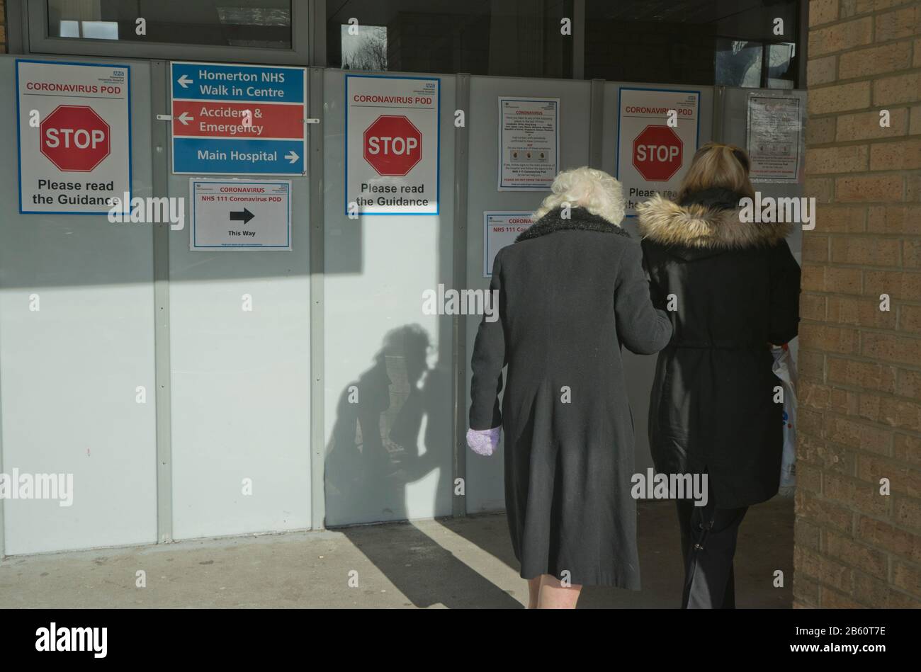 Les visiteurs âgés marchent devant les panneaux indiquant Coronavirus pod à l'hôpital NHS de Homerton à Londres, en Angleterre, au Royaume-Uni Banque D'Images