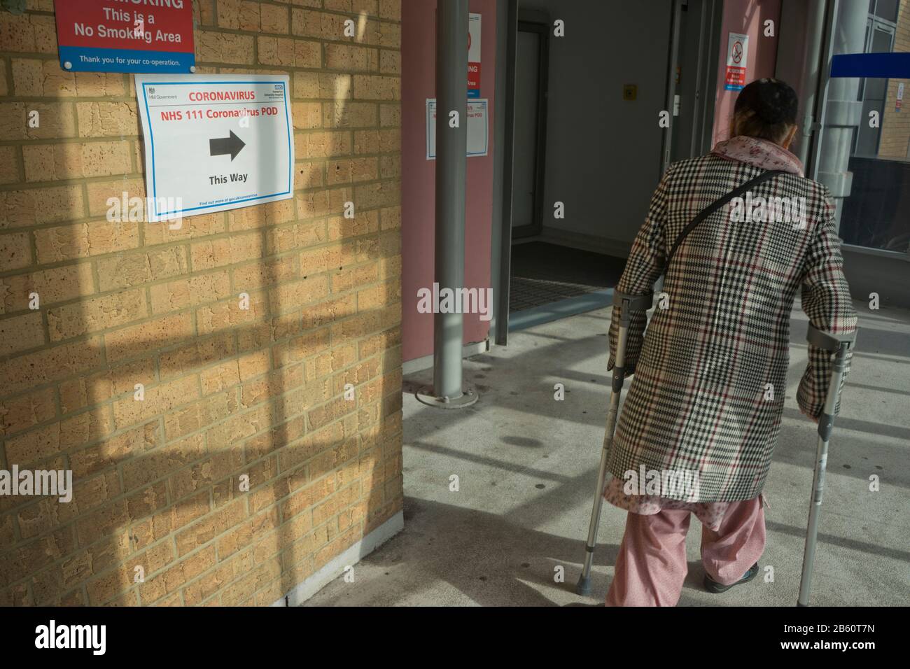 Les visiteurs âgés marchent devant les panneaux indiquant Coronavirus pod à l'hôpital NHS de Homerton à Londres, en Angleterre, au Royaume-Uni Banque D'Images