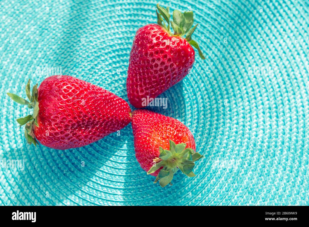 gros plan de fraises rouges rafraîchissantes sur une surface plane bleue Banque D'Images