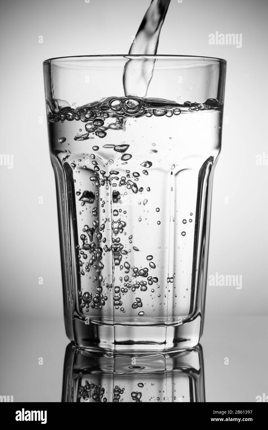 De l'eau pure qui coule dans un verre. Sur fond gris. Banque D'Images