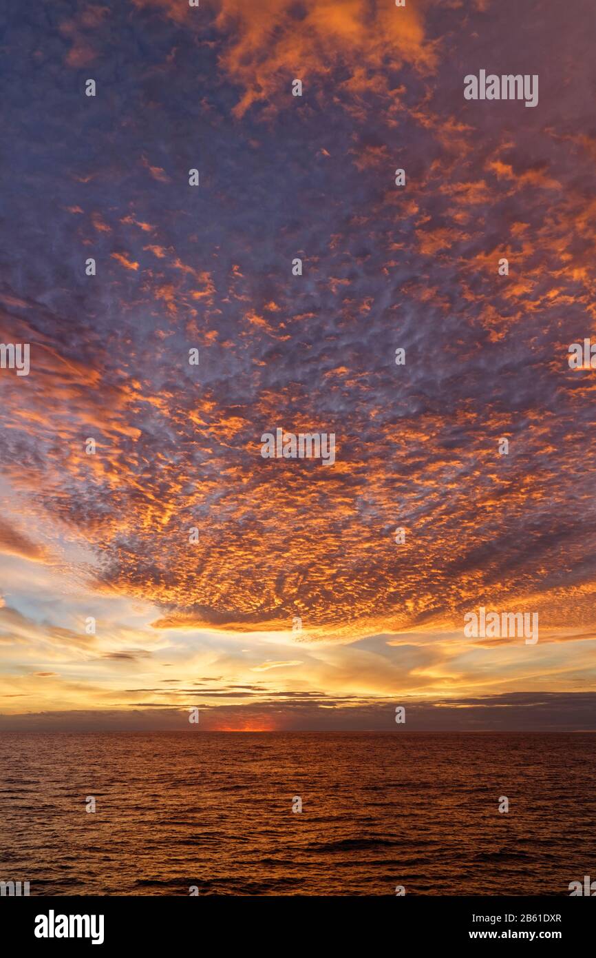 Le soleil couchant illumine de manière spectaculaire les nuages bas lors d'une soirée de Summers au-dessus des eaux calmes de la mer d'Irlande du Sud. Banque D'Images