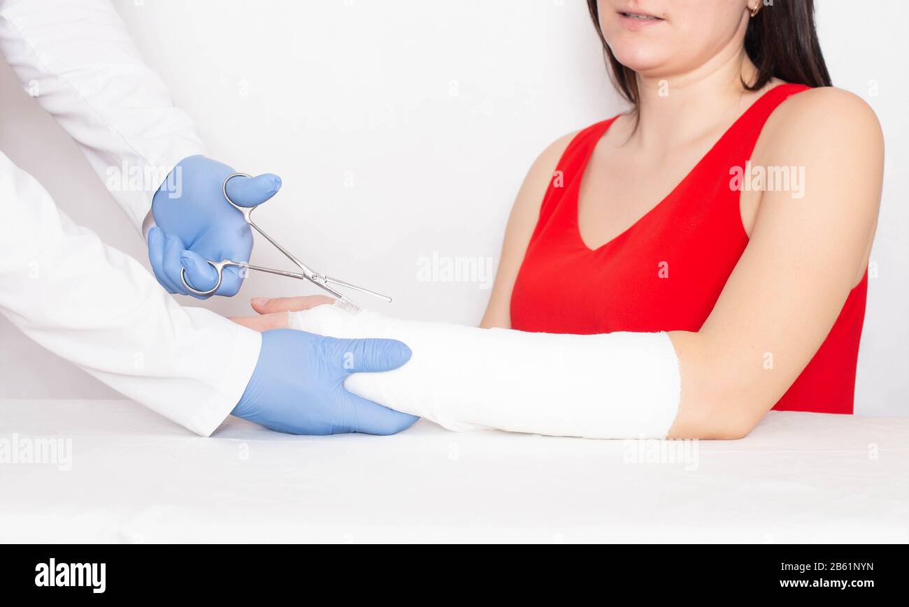 Le traumatologue de docteur coupe un plâtre d'une jeune fille sur son bras avec une fracture du rayon sans déplacement Banque D'Images
