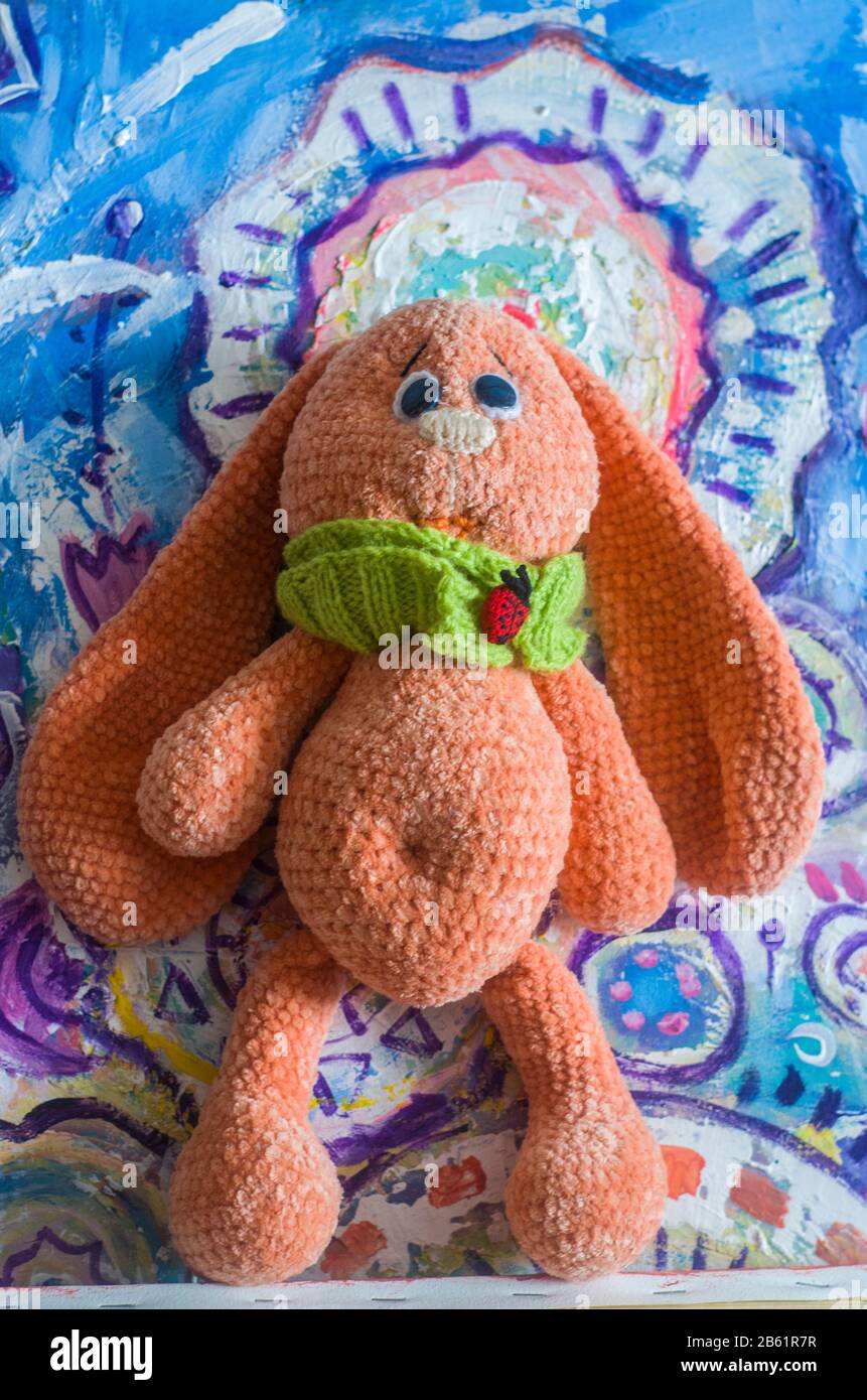 Tricoté lapin jouet abricot couleur sur un arrière-plan pittoresque. Photo de Pâques. Banque D'Images
