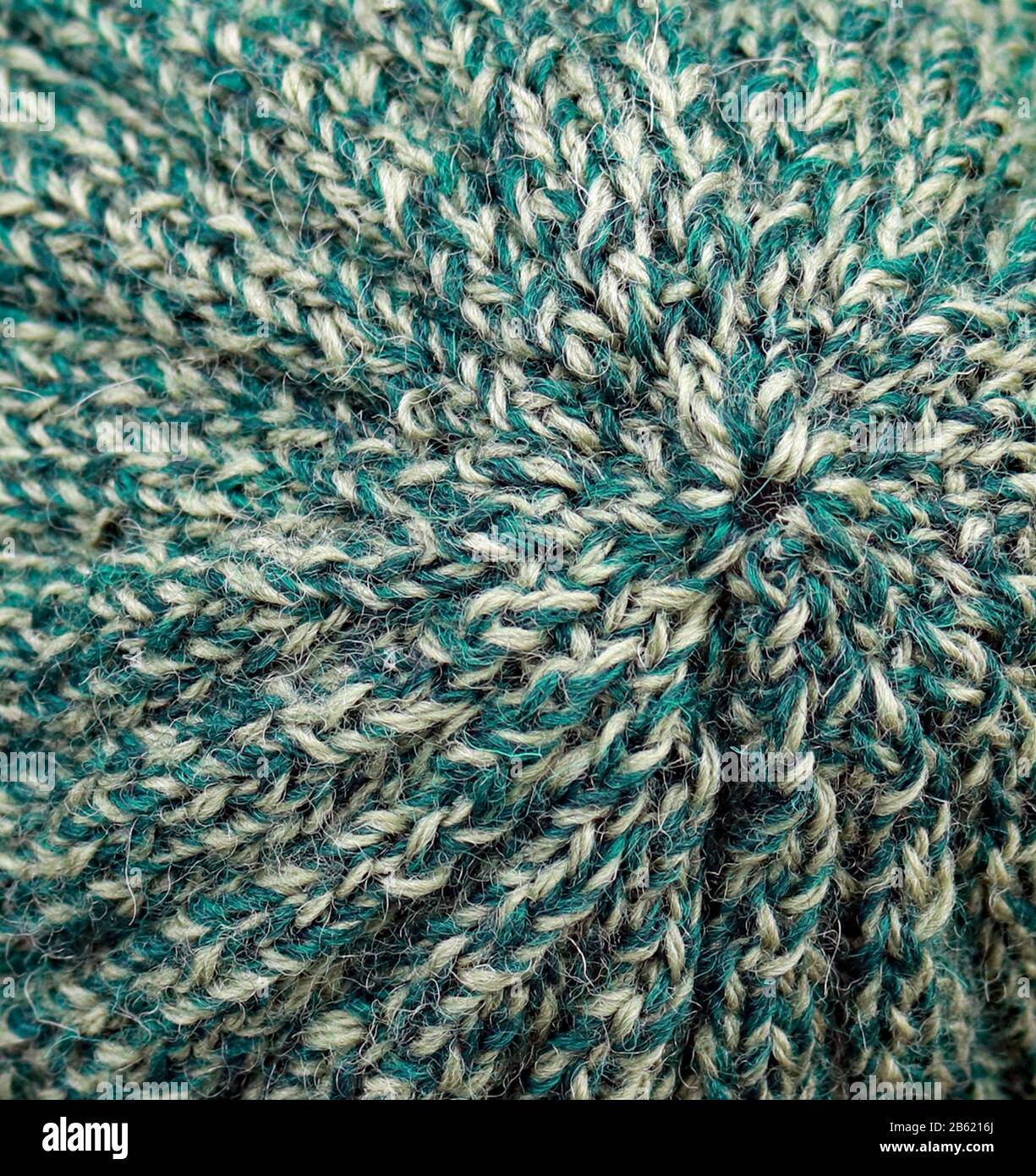 Un chapeau à côtes texturé pour adultes est tricoté à la main de pure laine britannique dans des tons de vert tweedy. Banque D'Images