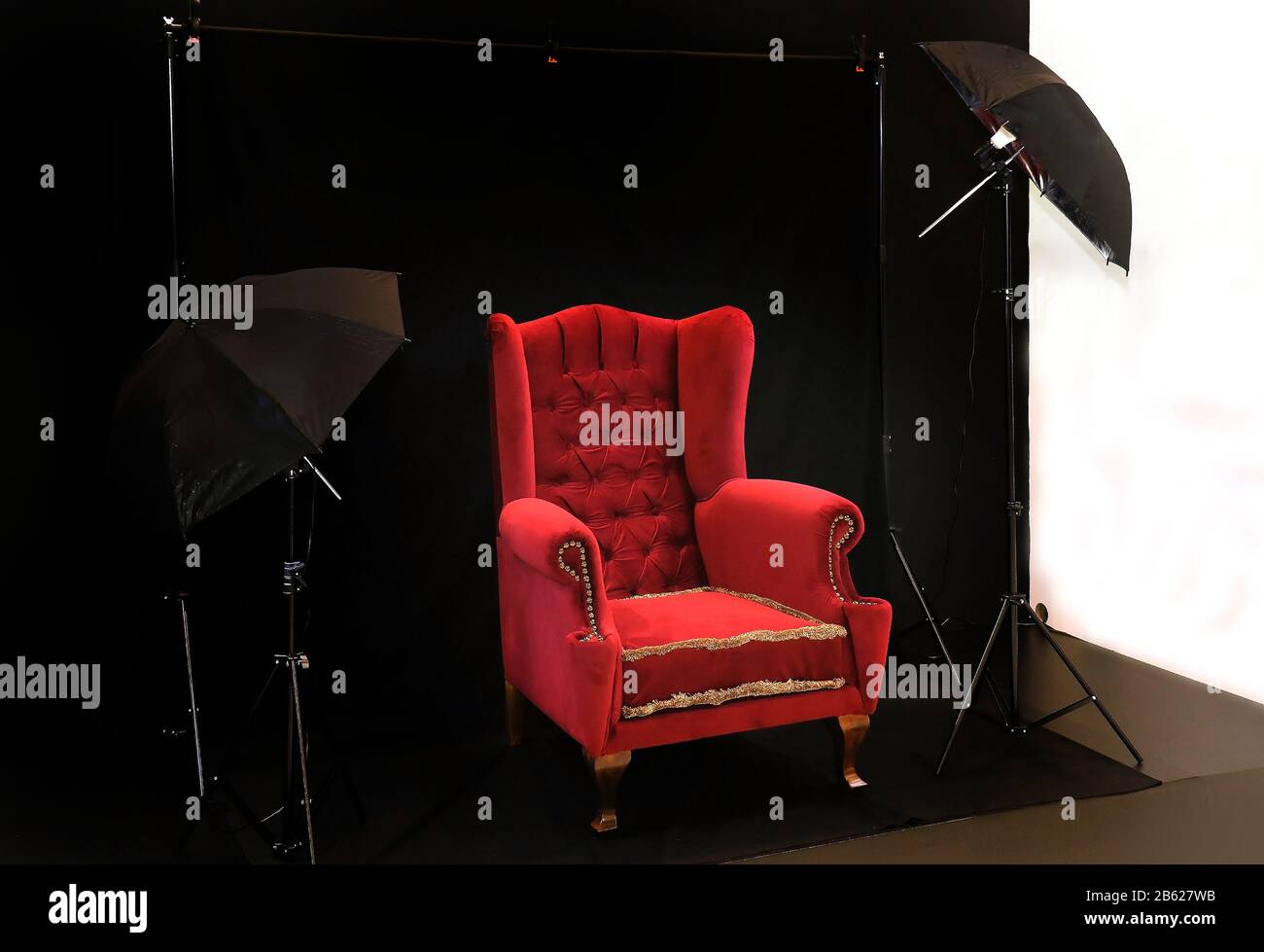 Petit studio avec fauteuil rétro qui doit être photographié et équipement d'éclairage professionnel Banque D'Images