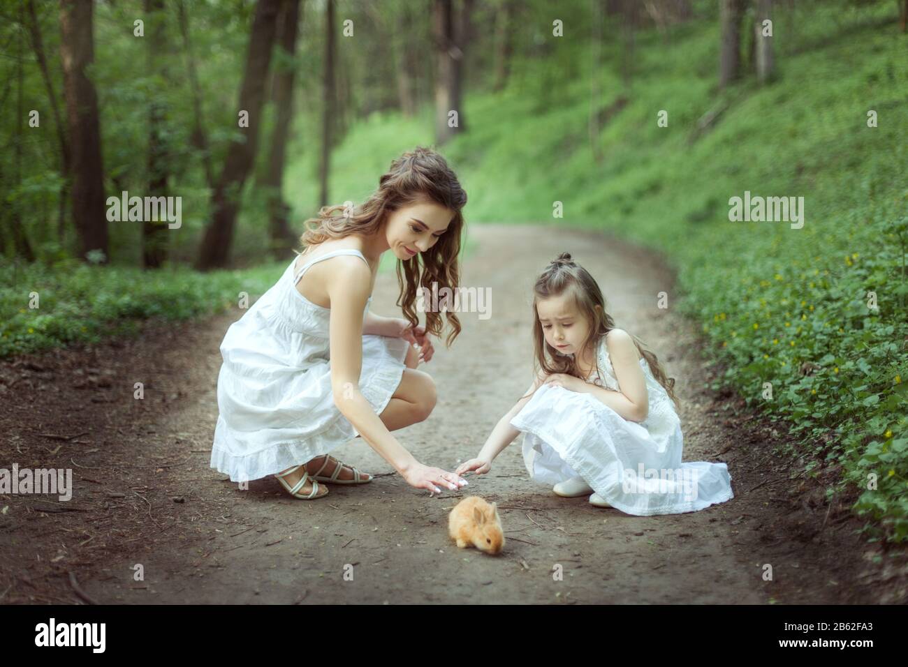 Portrait d'une jeune mère avec sa fille dans la forêt avec un petit lapin. Banque D'Images