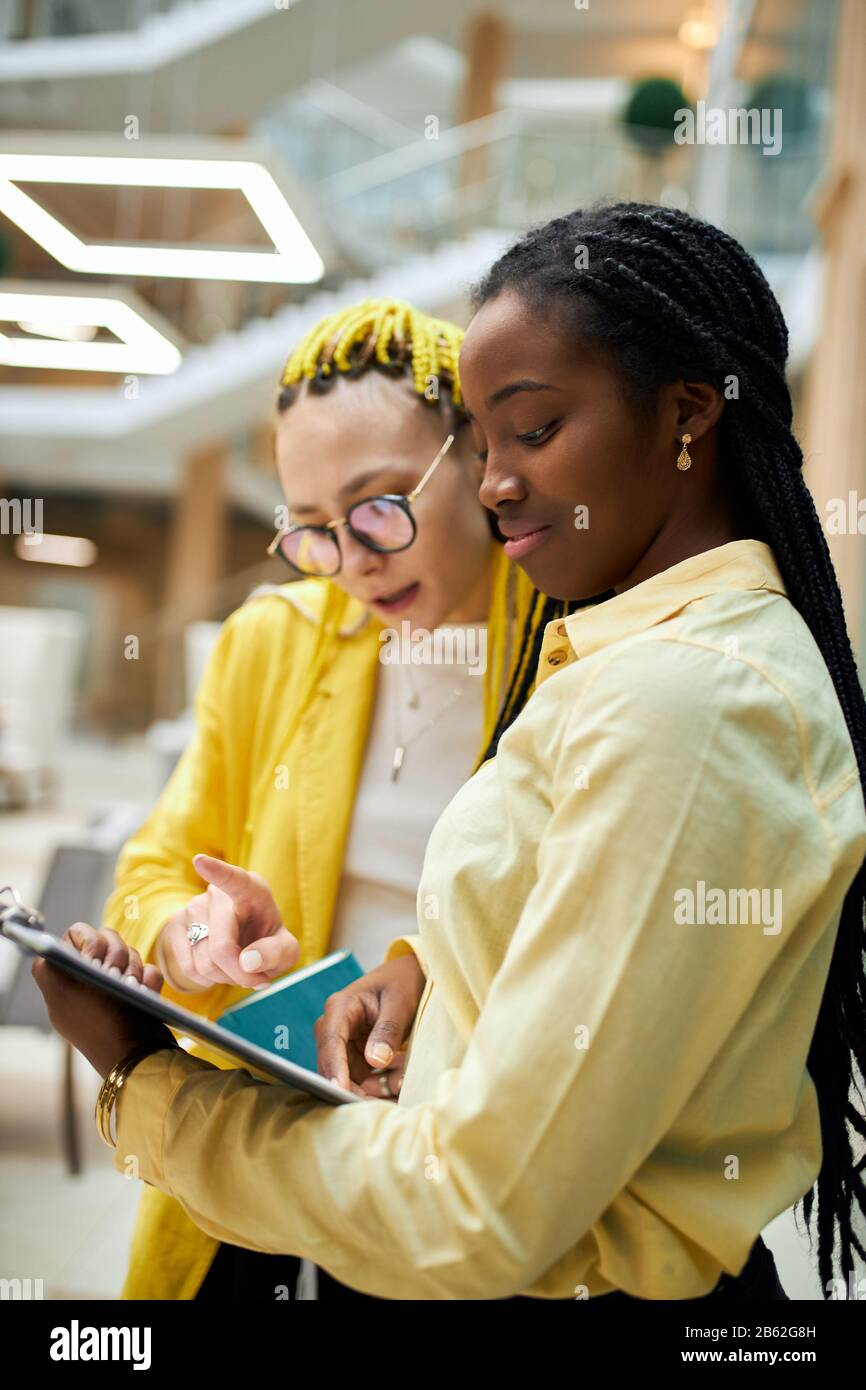 afro attrtiva crème anglaise en jaune élégant blose consultant client, gros plan photo, belle femme pointant vers le document qui est Banque D'Images