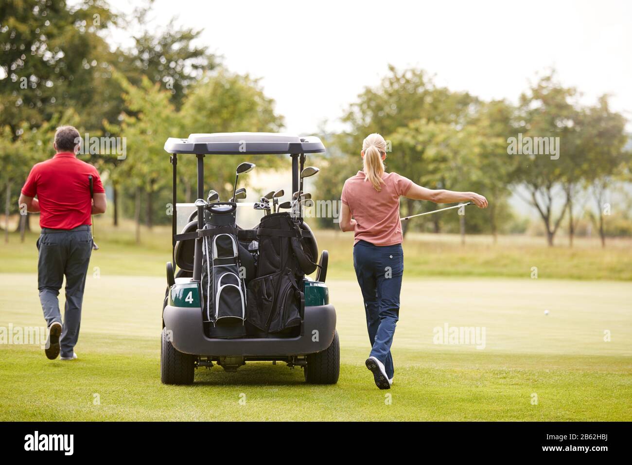 Vue Arrière Du Couple Sortir Du Golf Buggy To Play Shot On Green Banque D'Images