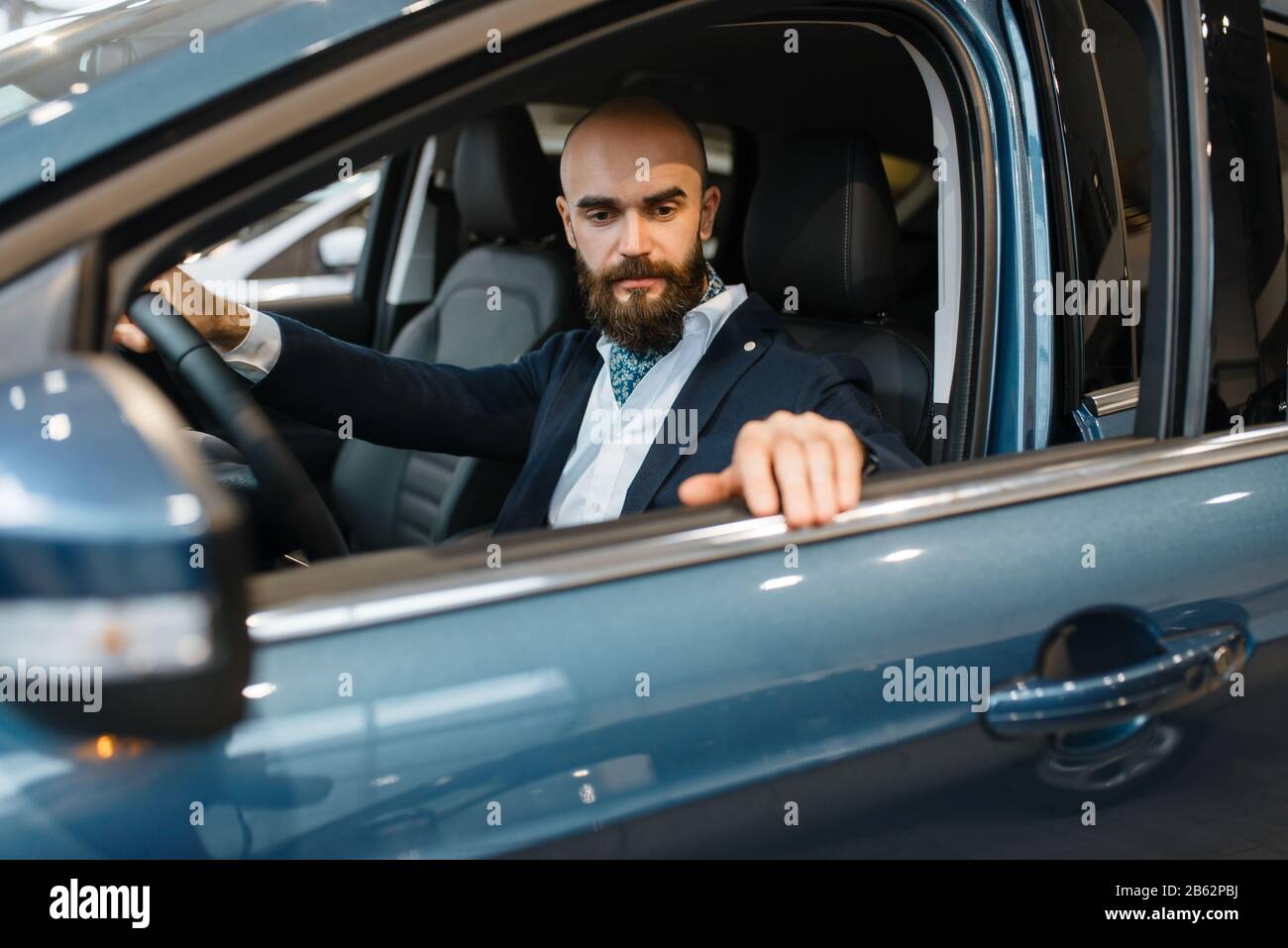 Homme souriant pose dans l'automobile, la concession automobile Banque D'Images