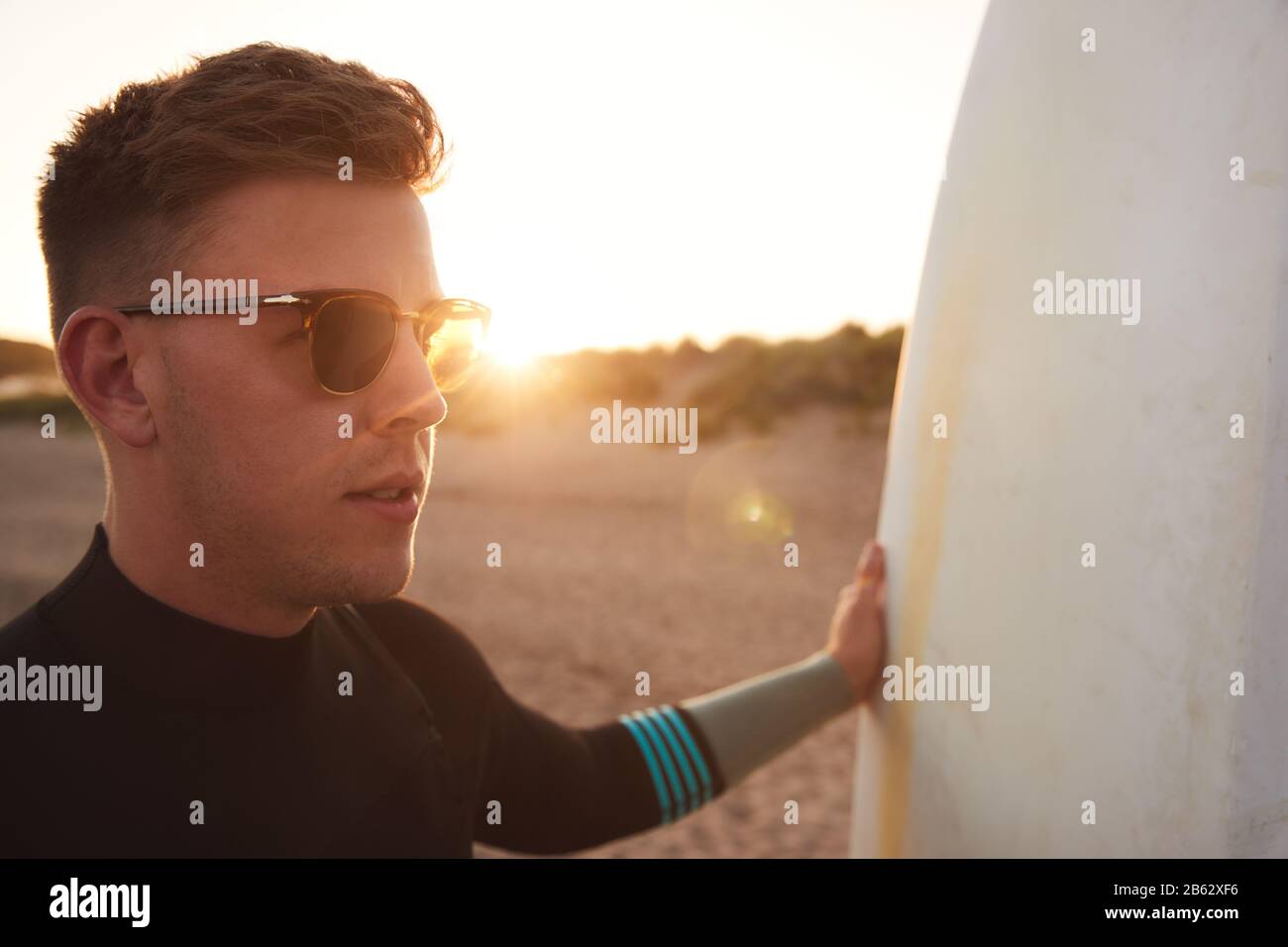 Jeune Homme À Lunettes De Soleil Portant Un Costume De Plage En Profitant  De La Staycation De Surf Sur La Plage En Tant Que Sun Sets Photo Stock -  Alamy