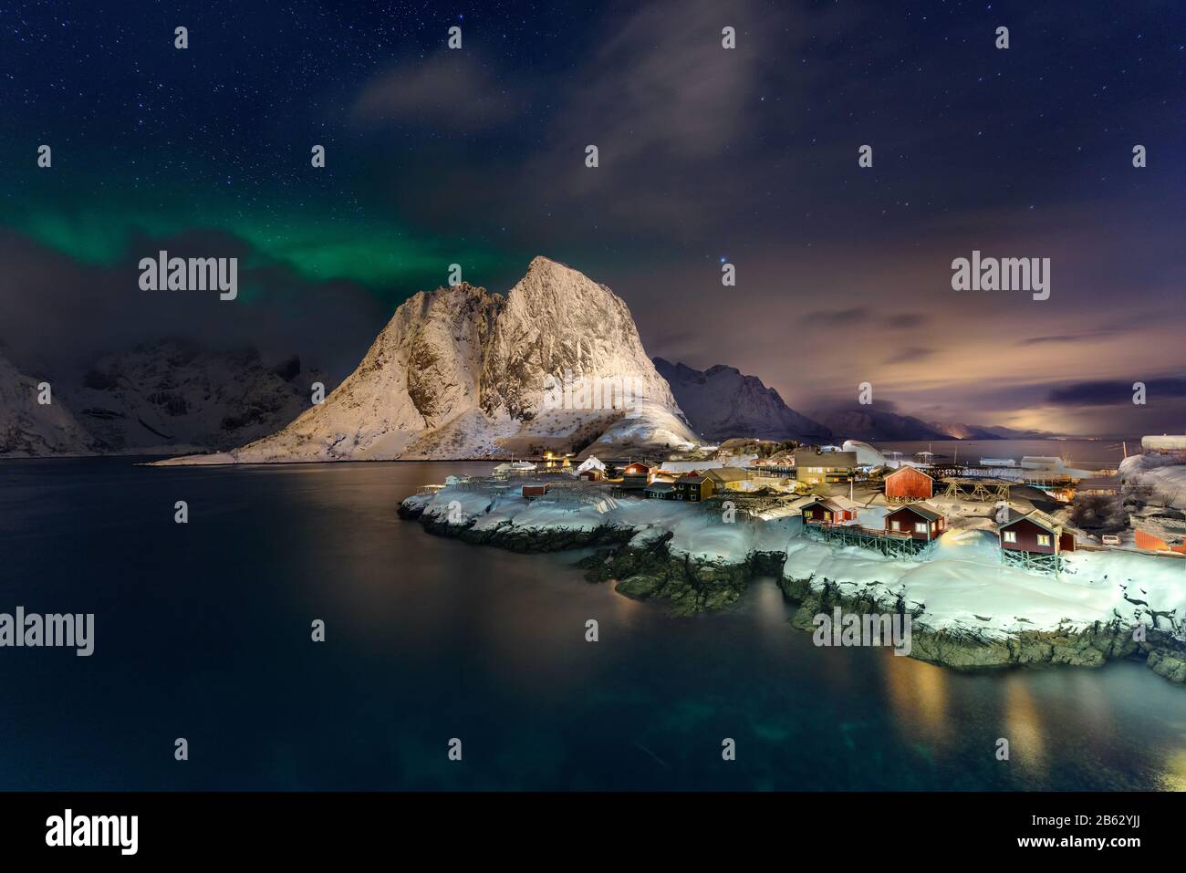 Magnifiques Aurores Boréales À Hamnoy, Île Lofoten En Norvège. Aurora Boréal au-dessus du petit village de pêcheurs avec ses huttes rouges traditionnelles. Majestueux gr Banque D'Images