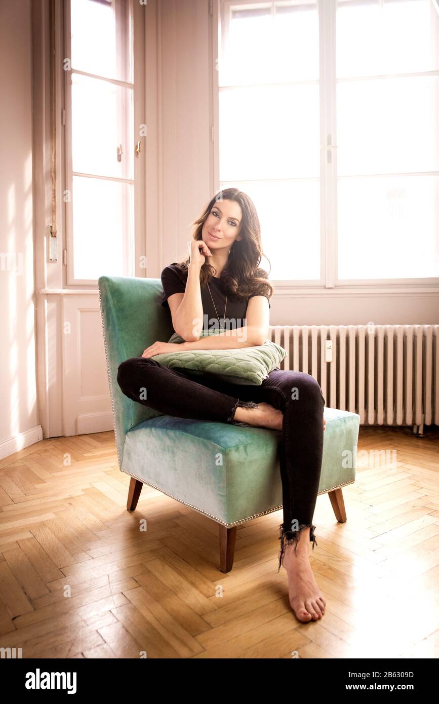 Photo pleine longueur d'une belle femme se relaxant à la maison dans le fauteuil. Banque D'Images