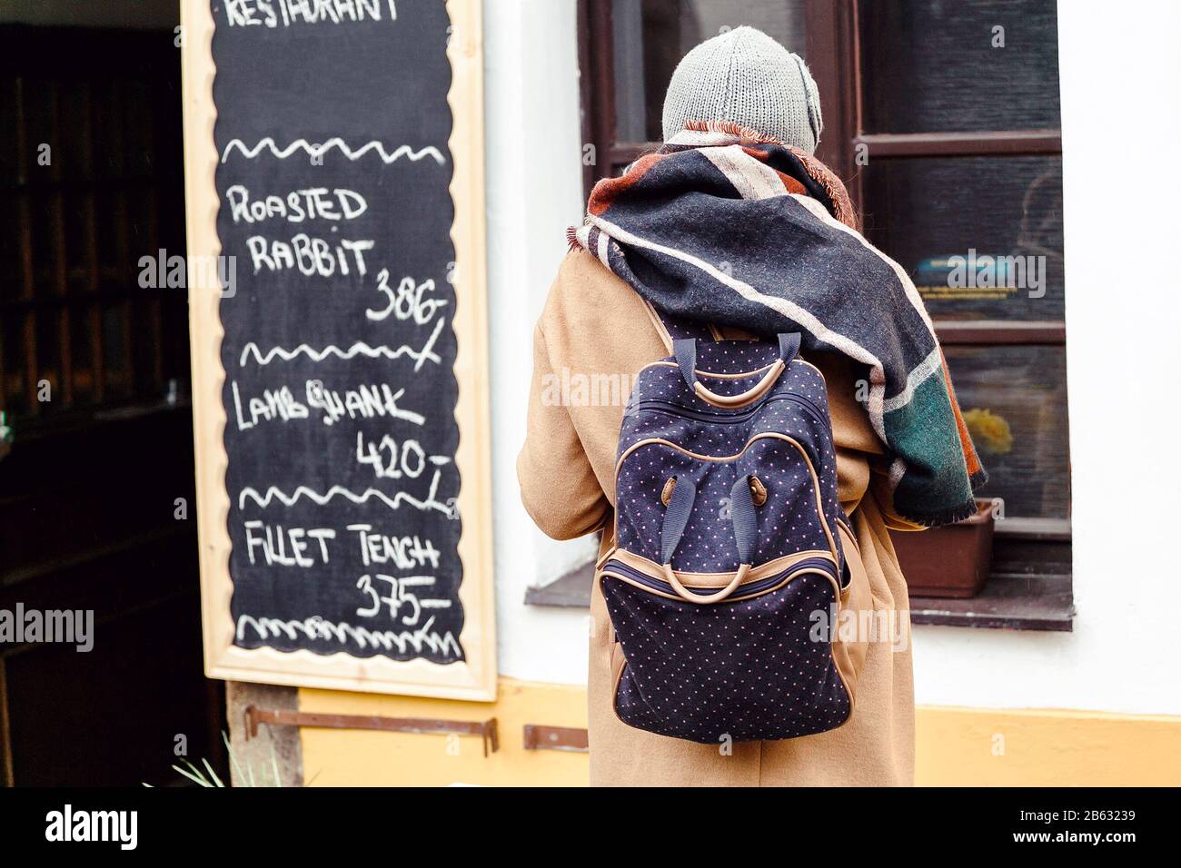 Femme touriste avec sac à dos à l'automne regardant le menu du restaurant avec le prix en Europe Banque D'Images