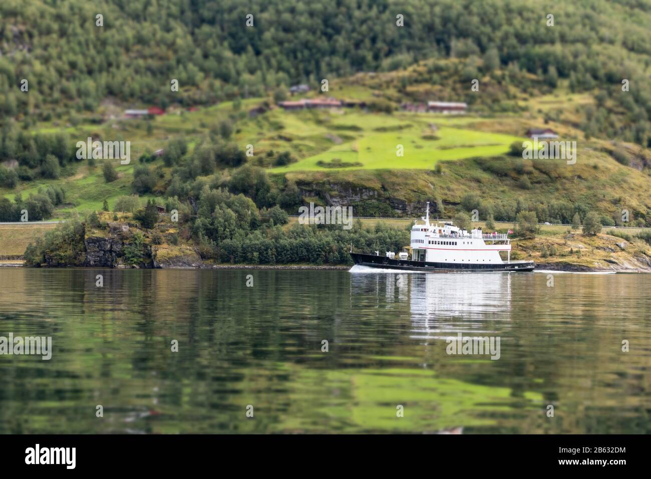 Petit navire sur la surface de l'eau verte miroir avec reflet du fjord norvégien Aulandsfjord. Arrière-plan flou. Vue imprenable sur la nature de la Norvège. Ensoleillé Banque D'Images