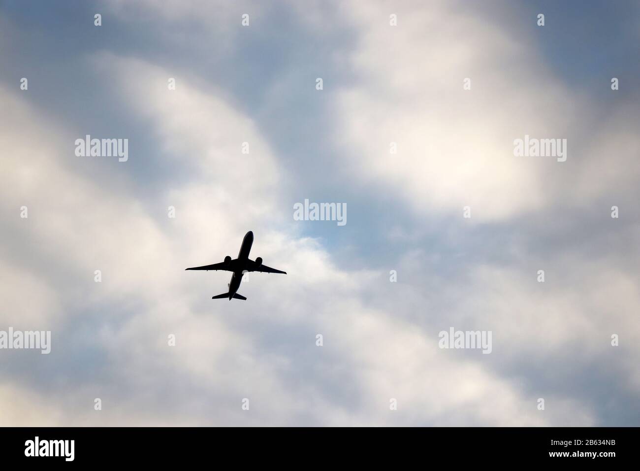 Avion volant dans le ciel bleu sur fond de nuages blancs. Silhouette d'un avion commercial pendant le concept de montée, de voyage et de turbulence Banque D'Images