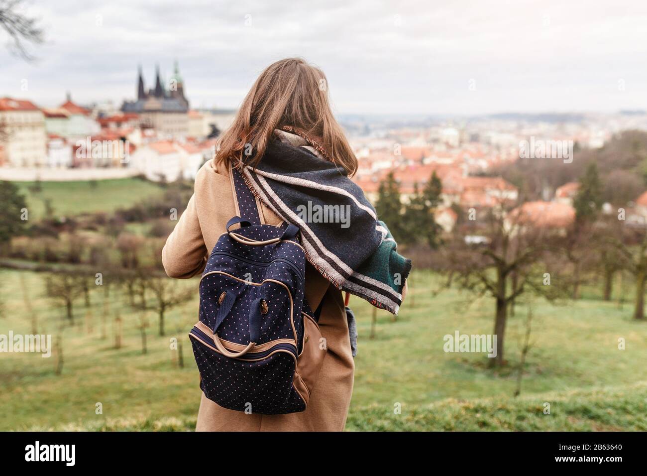 Femme touriste dans un manteau avec un sac à dos voyage dans le parc de Prague, vue arrière Banque D'Images