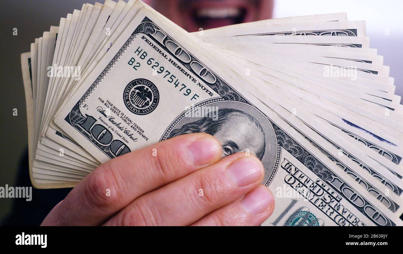 Une pile de billets de 100 dollars entre les mains d'un homme Banque D'Images