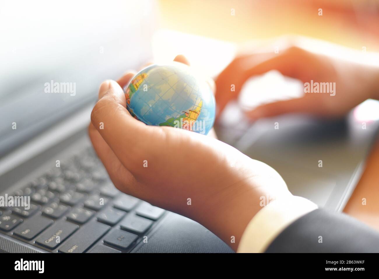 Homme d'affaires tenant le modèle globe terrestre à portée de main et utiliser un ordinateur portable / technologie d'affaires à l'échelle mondiale et autour du concept mondial Banque D'Images
