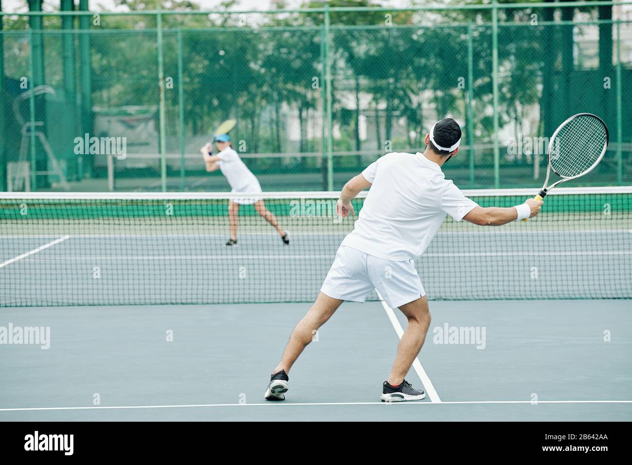 Couple en uniforme blanc ayant un match de tennis sur le court Banque D'Images