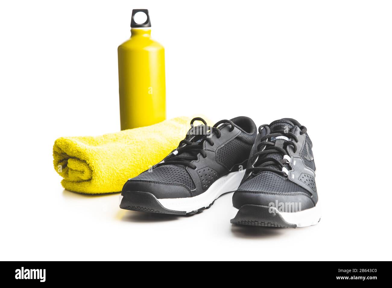 Chaussures de sport noires, serviette et bouteille isolées sur fond blanc. Banque D'Images
