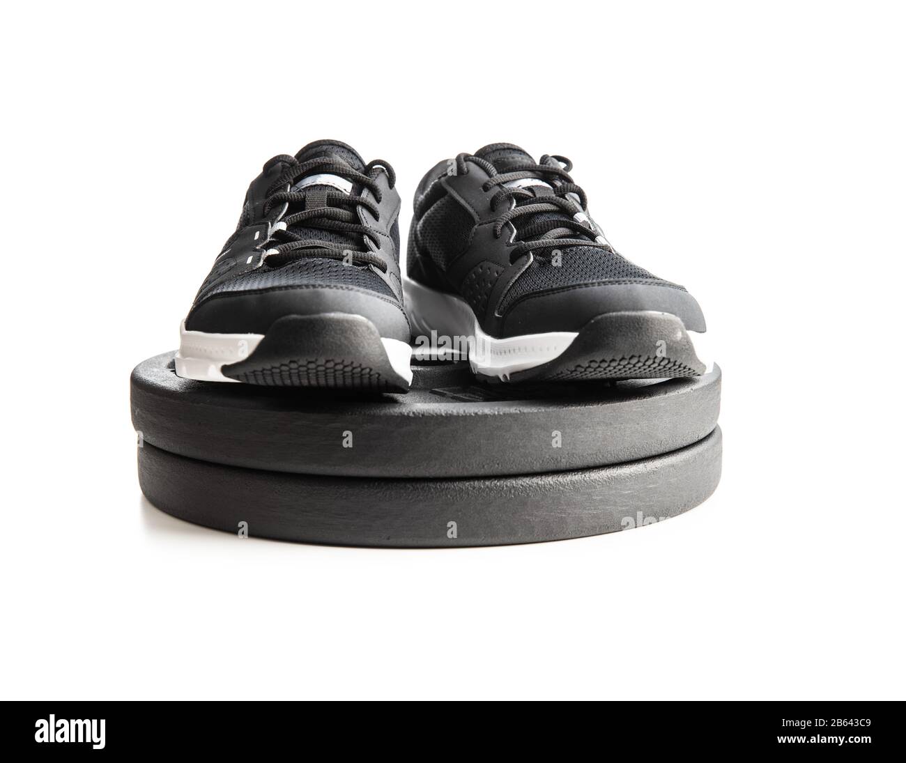 Chaussures et haltères de sport noires isolées sur fond blanc. Banque D'Images