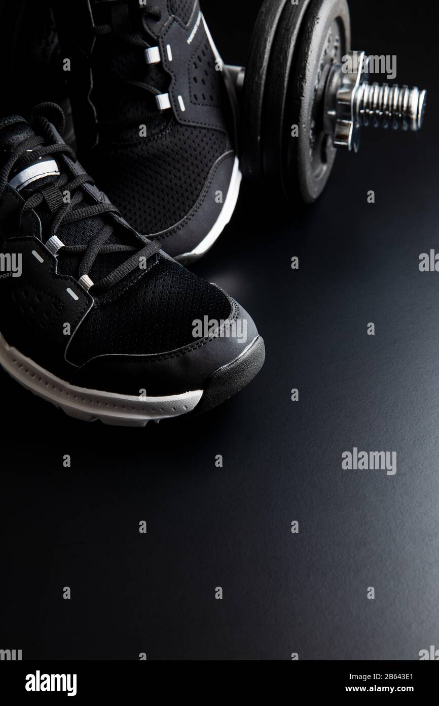 Concept de forme physique. Chaussures de sport noires sur fond noir. Banque D'Images