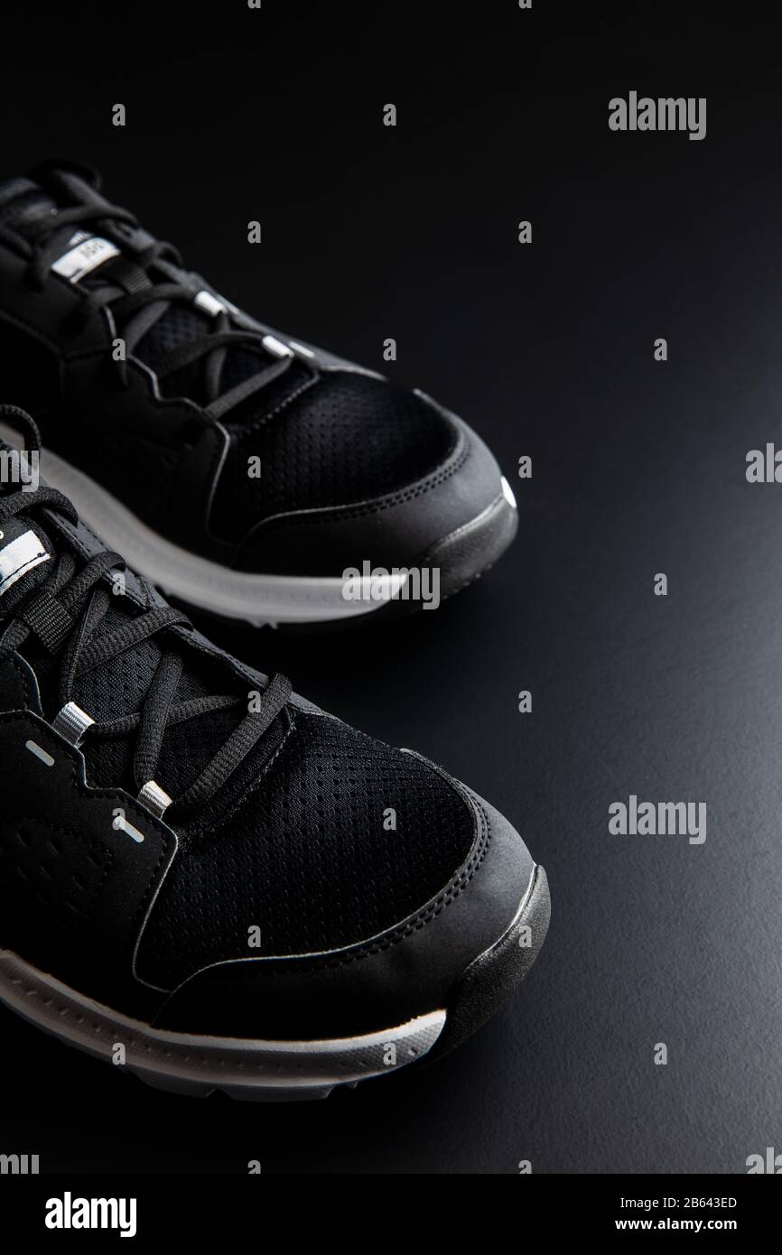 Chaussures de sport noires sur fond noir. Banque D'Images
