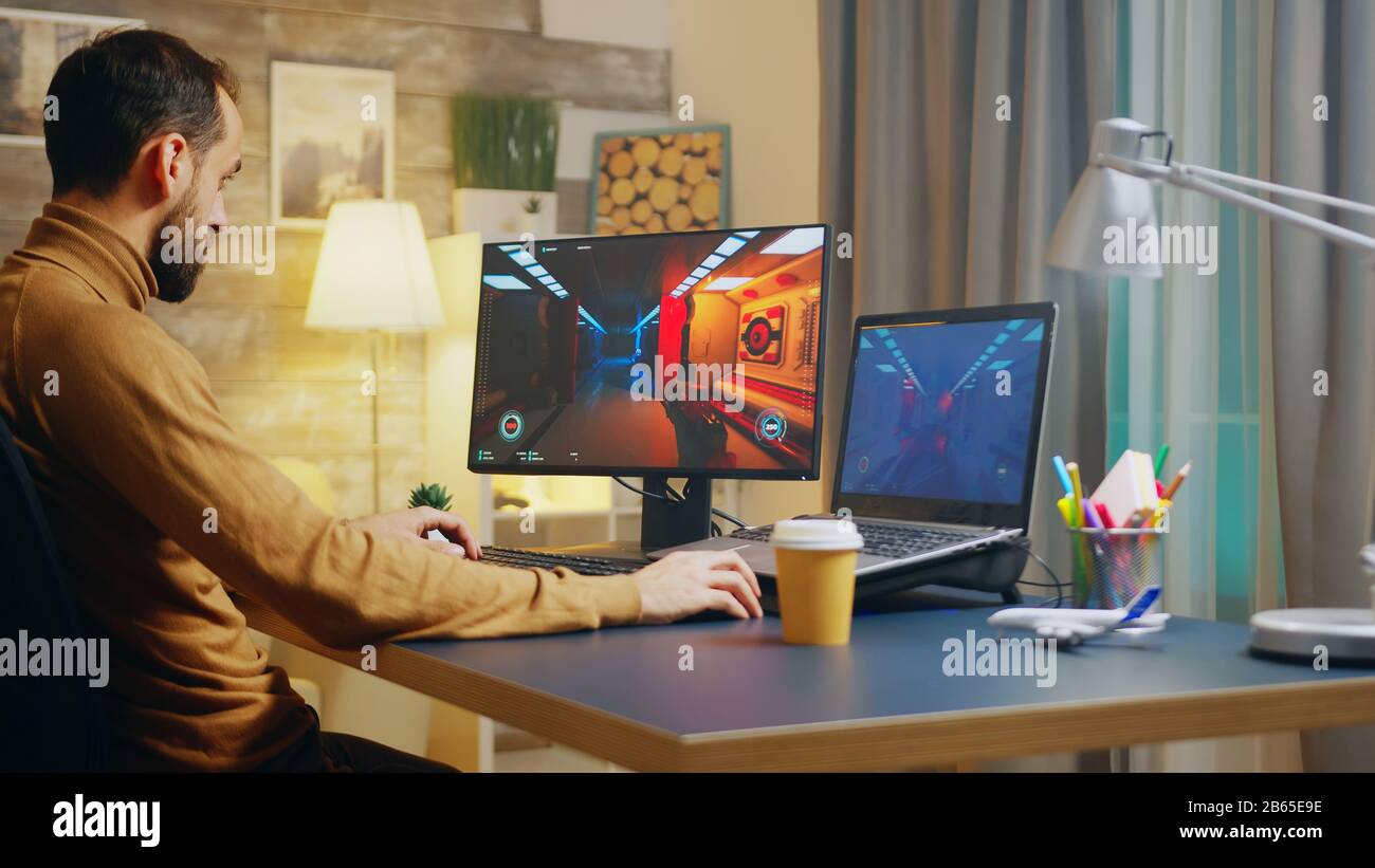 Jeune créateur de jeu testant l'interface du jeu de tir. Développeur de jeux travaillant la nuit. Banque D'Images