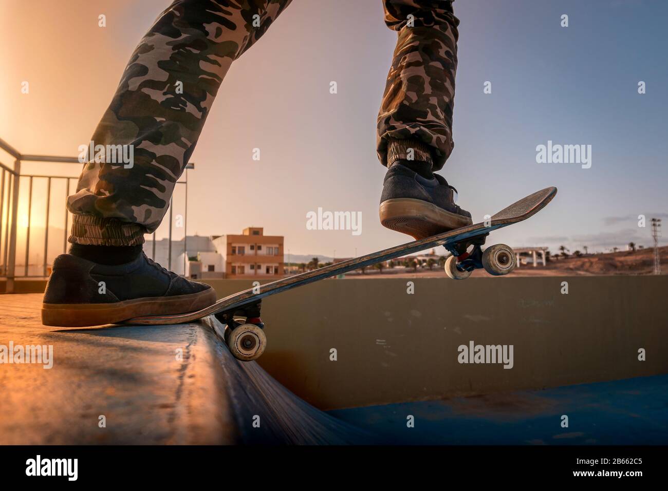 gros plan sur les jambes d'un skateboarder sur le point de sauter avec son  skateboard sur une rampe au coucher du soleil Photo Stock - Alamy