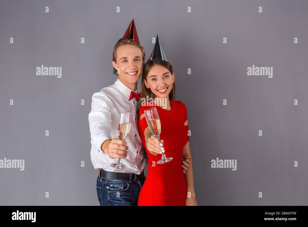 Jeune couple studio isolé sur le concept de mur gris Banque D'Images