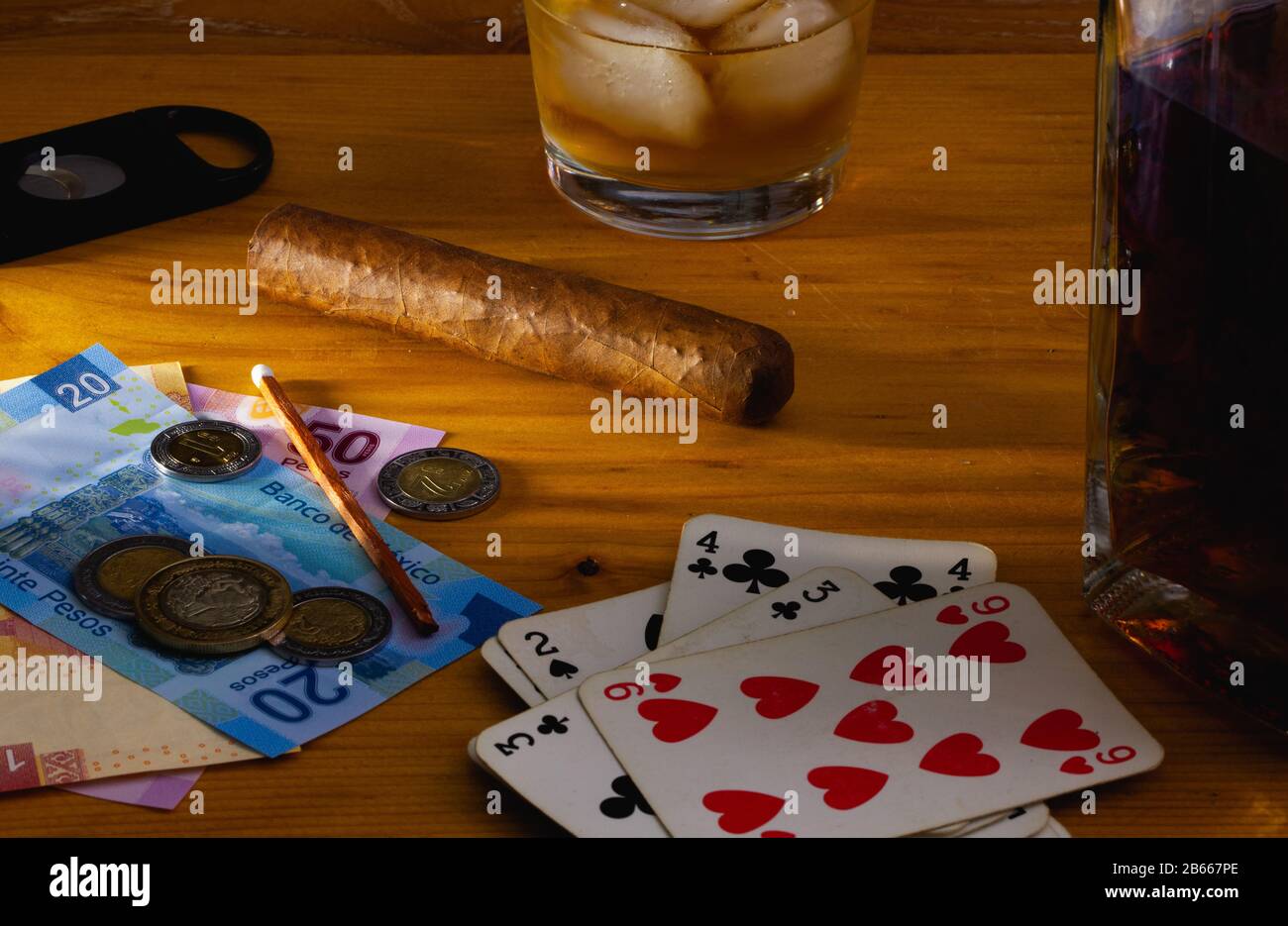 Jeu - tabac Cigar , cartes à jouer, whisky écossais et billets de banque au mexique sur la table en bois Banque D'Images