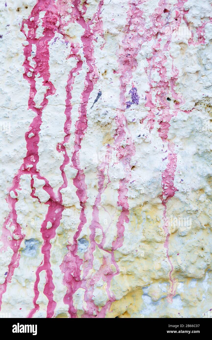 Gros plan d'un mur de stuc rugueux et plâtré peint en blanc. Gouttes et taches de peinture rose. Arrière-plan texturé plein format haute résolution. Banque D'Images