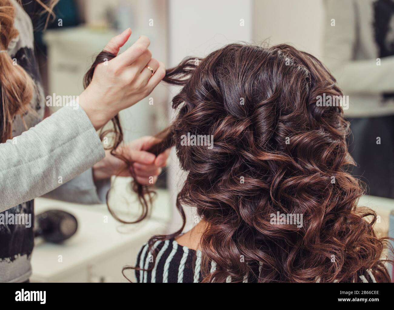 Close up of hands de coiffeur professionnel à salon de cheveux des femmes, le curling Banque D'Images