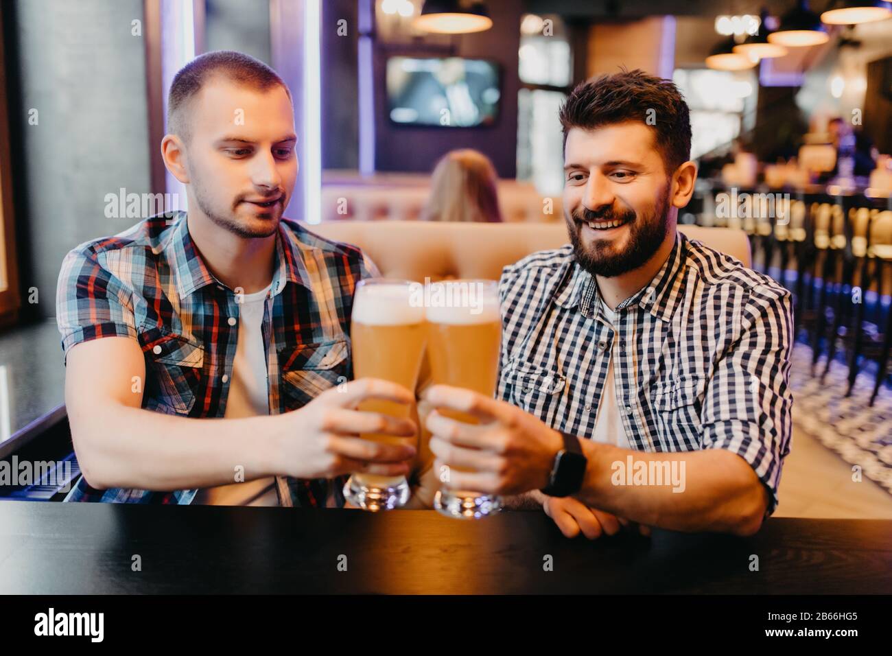 Heureux amis boire une bière et clinking glasses au bar ou au pub Banque D'Images