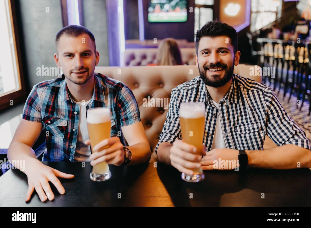 Heureux amis boire une bière et clinking glasses au bar ou au pub Banque D'Images