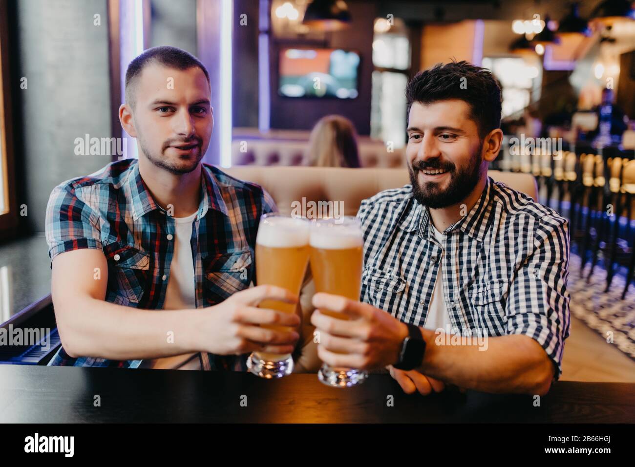 Deux hommes boivent de la bière au bar, la bière de clinking s'amuse au ...