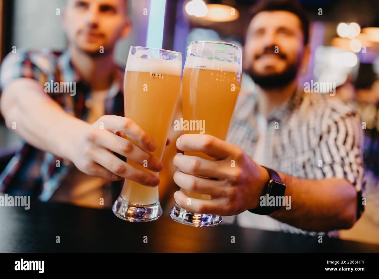 Des amis dégustant des verres de bière légère au pub. Un groupe de jeunes tout en se relaxant au bar. Banque D'Images