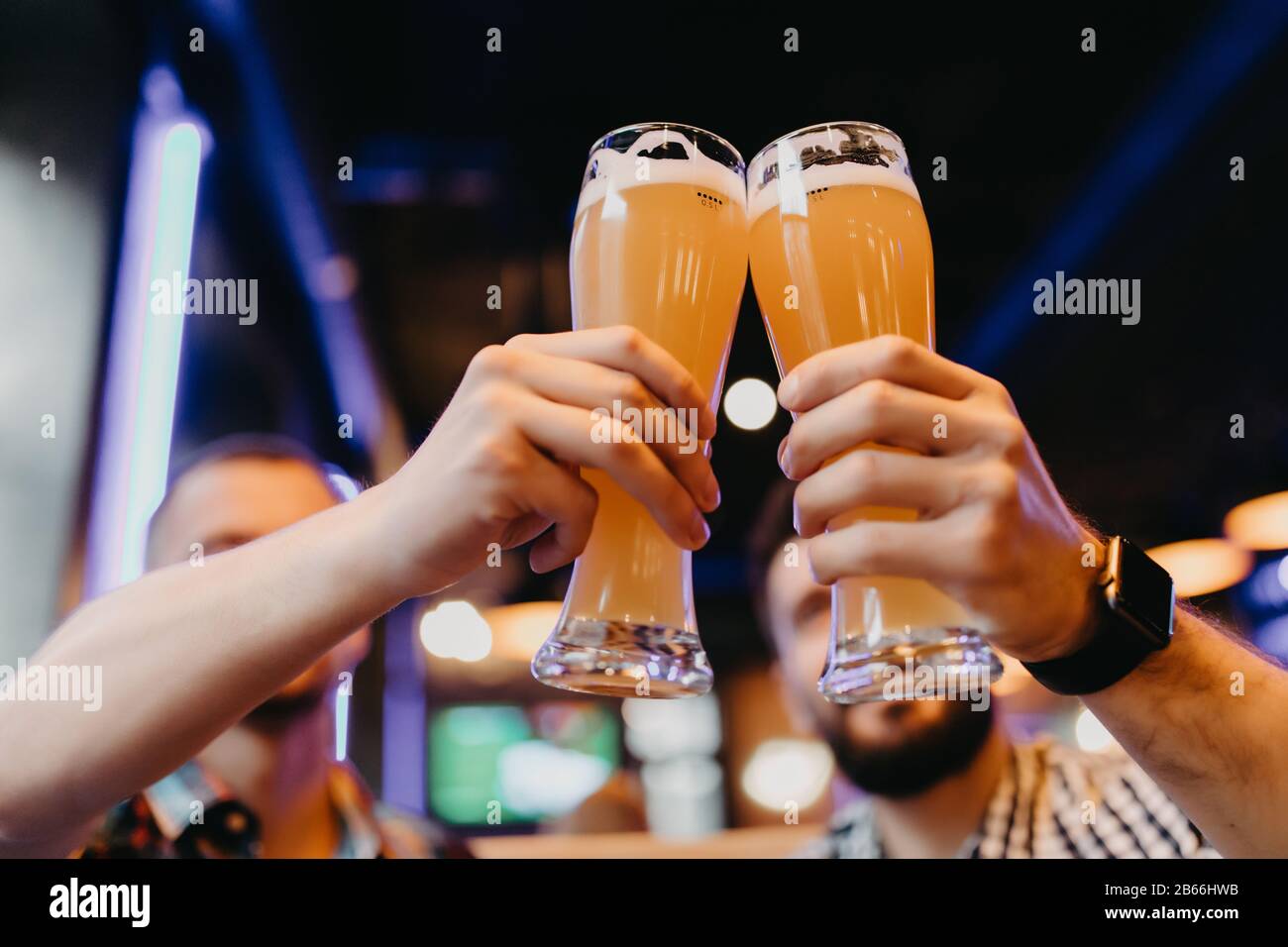 Des amis dégustant des verres de bière légère au pub. Un groupe de jeunes tout en se relaxant au bar. Banque D'Images