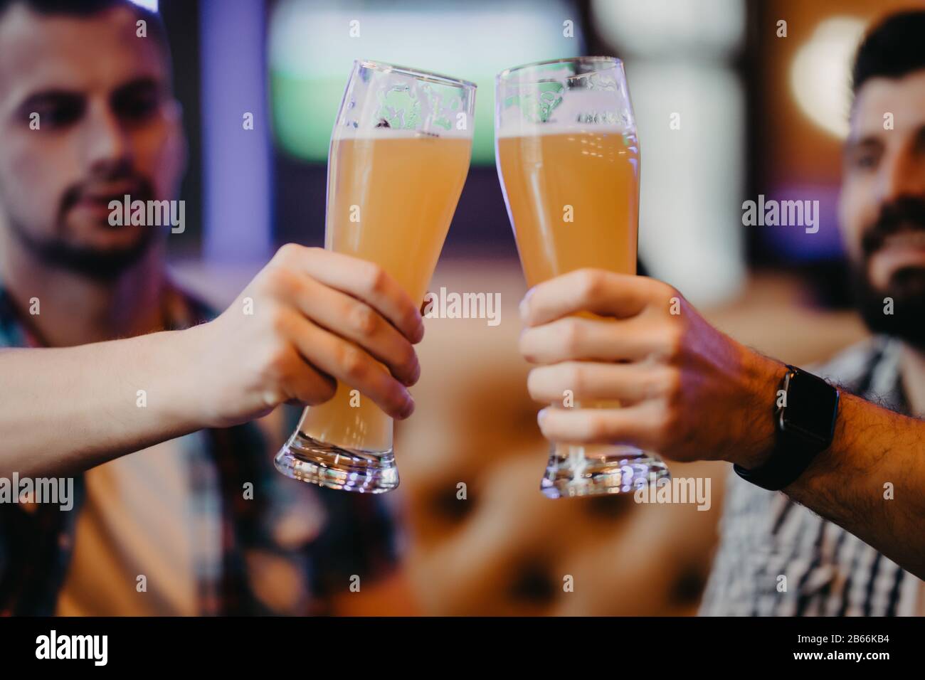 Gros plan sur les mains de deux amis en dégustant des verres de bière au pub. Banque D'Images