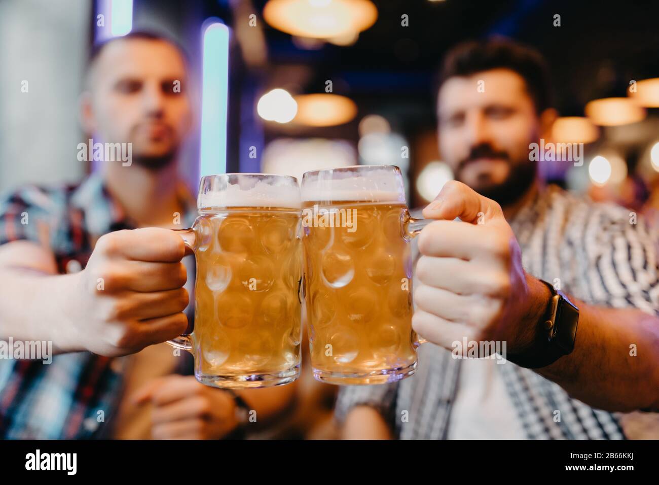 Les amis sont des verres de bière et souriants tout en se reposant au pub Banque D'Images