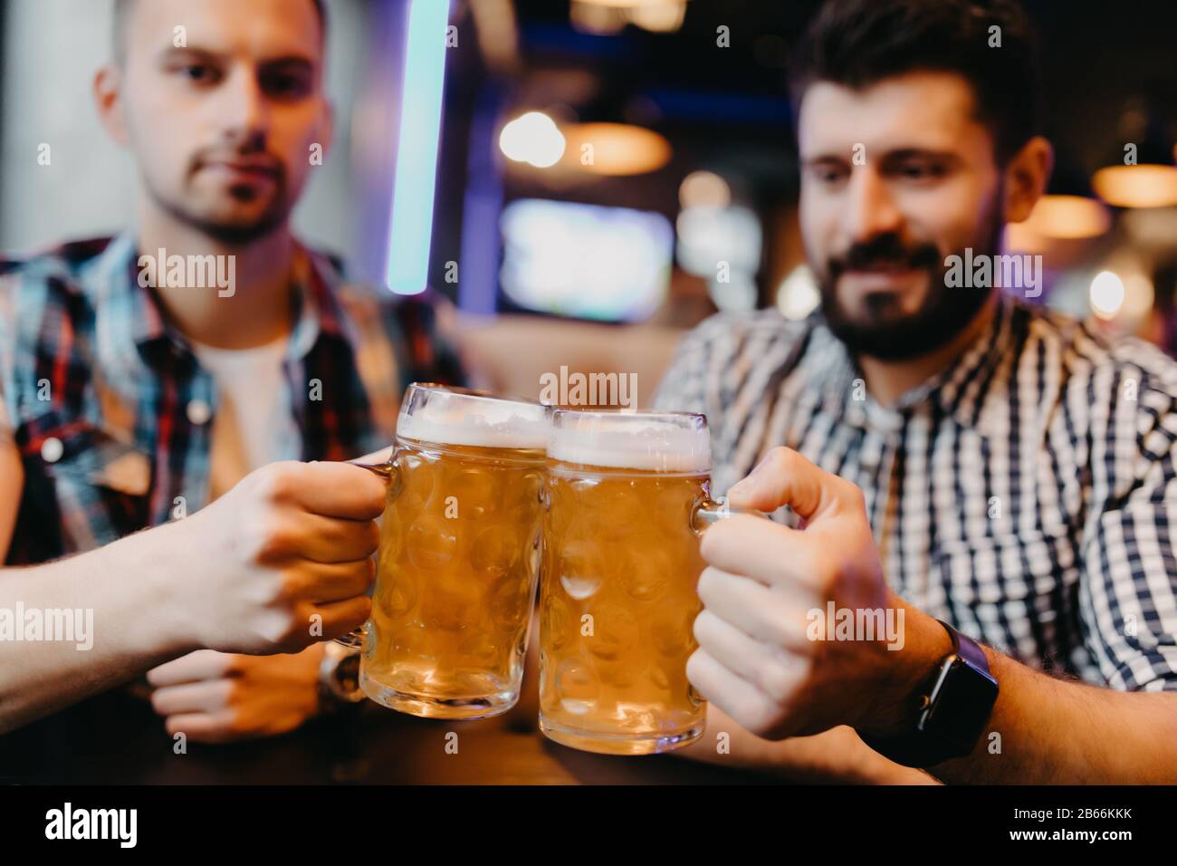 Les amis sont des verres de bière et souriants tout en se reposant au pub Banque D'Images