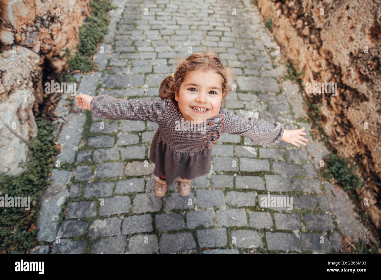 Une jolie fille de bébé tient les bras ouverts et marche sur un sentier sur une allée médiévale Banque D'Images